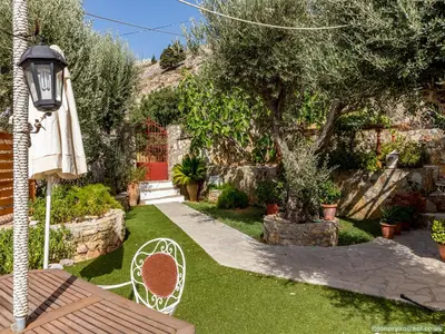a garden with a bench and an umbrella and a tree at Fotinis Cottage in Symi