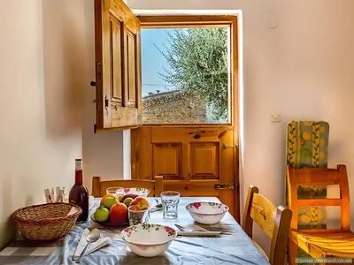 a table with bowls of fruit on it with a window at Fotinis Cottage in Symi