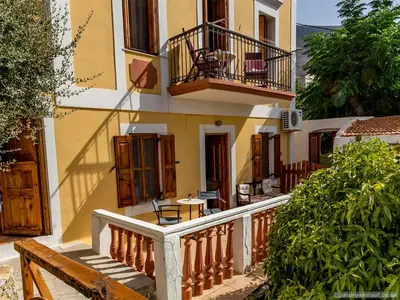 a building with a balcony and a wooden bench at Fotinis Cottage in Symi