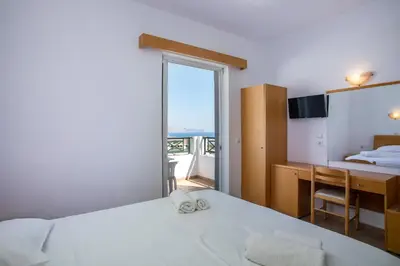 a bedroom with a bed and a desk and a window at Lambis Studios & Apartments in Líndos