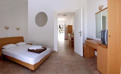 a bedroom with a bed and a desk and a tv at Lambis Studios & Apartments in Líndos