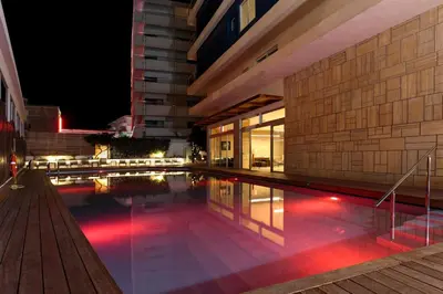 a swimming pool in front of a building at night at Athena Hotel in Rhodes Town