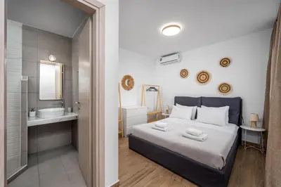 a bedroom with a bed and a bathroom with a sink at Hill & Sea View Villas in Kolimbia