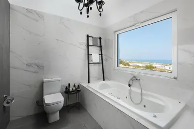 a bathroom with a tub and a toilet and a window at Hill & Sea View Villas in Kolimbia