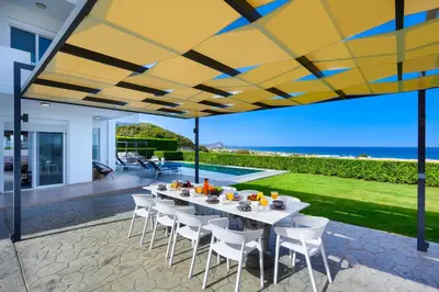 a patio with a table and chairs under a yellow umbrella at Hill & Sea View Villas in Kolimbia