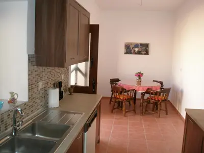 a kitchen with a sink and a table with chairs at Casa Theoni in Kattavía