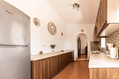a kitchen with white walls and wooden cabinets at Casa Theoni in Kattavía