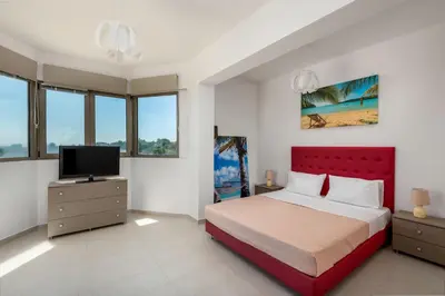 a bedroom with a red bed and a flat screen tv at Villa Anolia with Private Pool in Koskinou