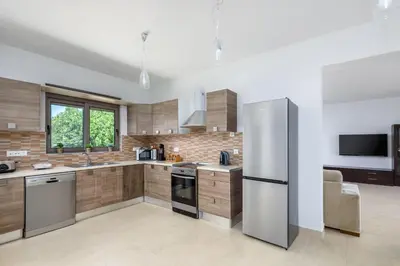 a kitchen with a stainless steel refrigerator and wooden cabinets at Villa Anolia with Private Pool in Koskinou