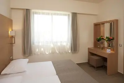 a bedroom with a white bed and a window at Island Blue Hotel in Pefki Rhodes