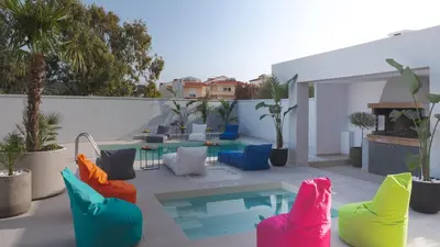 a patio with colorful chairs and a pool at Villa Stergos in Kremasti