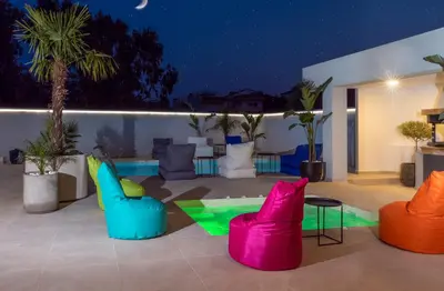 a patio with colorful chairs and a pool at night at Villa Stergos in Kremasti