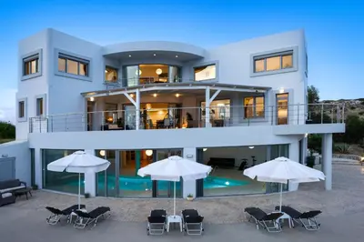 a large white house with chairs and umbrellas at Villa Zafira - Seaview Manor with Heated Pool in Kallithea Rhodes