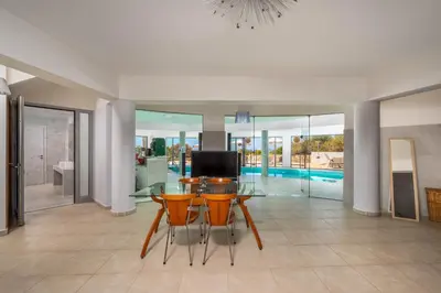 a living room with a table and chairs and a television at Villa Zafira - Seaview Manor with Heated Pool in Kallithea Rhodes