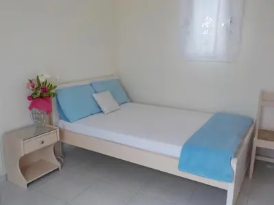 a white bed with blue pillows and a vase with flowers at Mini City Center Studio in Rhodes Town