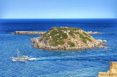 a small island in the ocean with a boat at Villa Elias in Archangelos