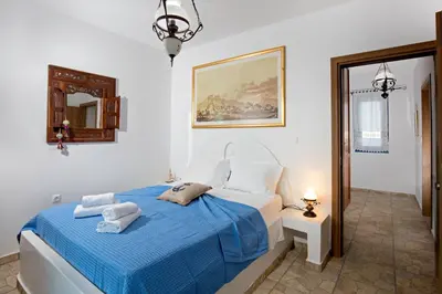 a bedroom with a bed with blue sheets and a mirror at Villa Elias in Archangelos