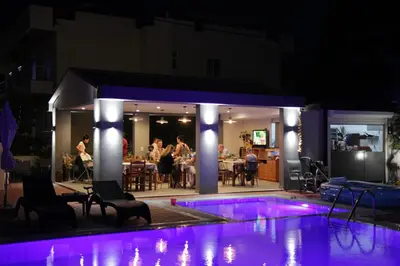 a swimming pool at night with people sitting around a restaurant at Platoni Elite in Ialyssos