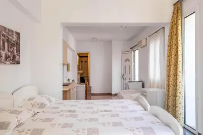a white bedroom with a bed and a bathroom at Sutherlea in Koskinou