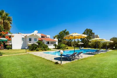 a pool with chairs and umbrellas in a yard at Sutherlea in Koskinou