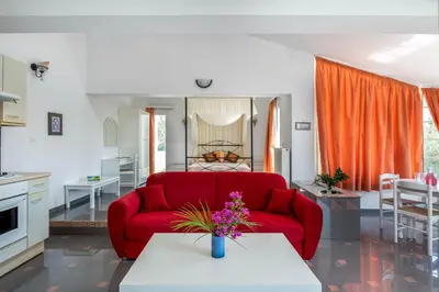 a living room with a red couch and a table at Sutherlea in Koskinou