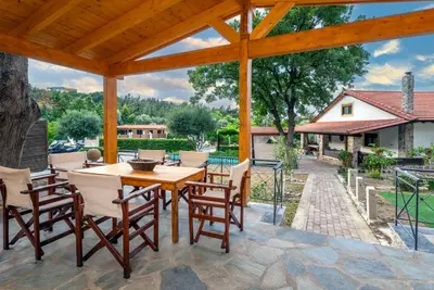 an outdoor patio with a wooden table and chairs at Villa Rafaela in Koskinou