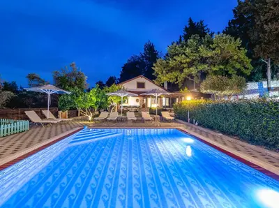a swimming pool in the backyard of a house at night at Villa Rafaela in Koskinou
