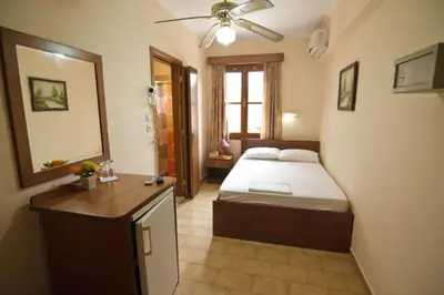 a bedroom with a bed and a desk and a mirror at Mango Rooms in Rhodes Town