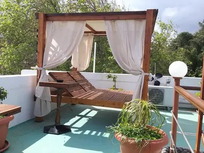a canopy bed on a balcony with plants at Mango Rooms in Rhodes Town