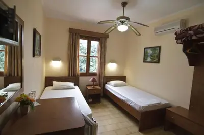 a bedroom with two beds and a ceiling fan at Mango Rooms in Rhodes Town