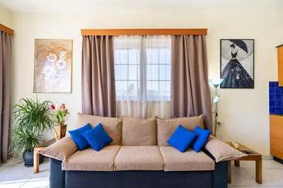 a living room with a couch with blue pillows at COLONIAL FAMILY apartment #3 in Faliraki