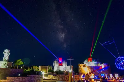 a night time view of a city with colorful lights at Astronomy Studios in Faliraki