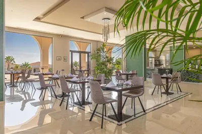 a restaurant with tables and chairs and a palm tree at KRESTEN ROYAL Euphoria Resort in Kallithea Rhodes