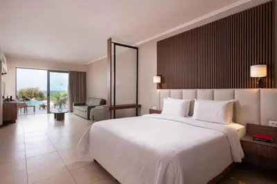 a bedroom with a large white bed and a living room at KRESTEN ROYAL Euphoria Resort in Kallithea Rhodes