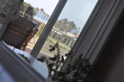 a window with a view of palm trees and a chair at Villa Imerti Kiotari in Kiotari
