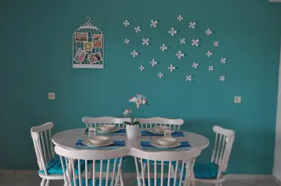 a dining room table with chairs and a bird cage on a blue wall at Villa Imerti Kiotari in Kiotari