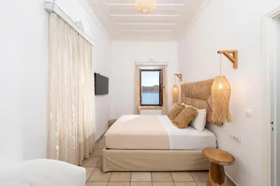 a white bedroom with a bed and a window at Villa Antonis in Halki