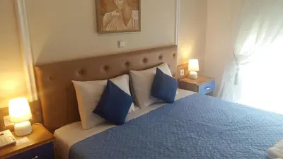 a bedroom with a blue bed with blue pillows at Pantheon Deluxe Apartments in Archangelos