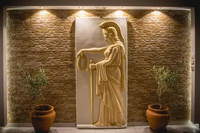 a statue of a goddess standing next to a brick wall at Pantheon Deluxe Apartments in Archangelos