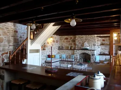 a living room with a table and a stone fireplace at Halkis Muses in Halki