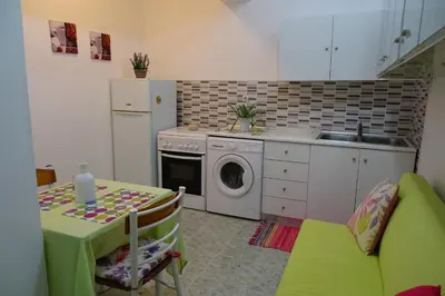 a kitchen with a table and a washing machine at Green Garden Studios in Koskinou