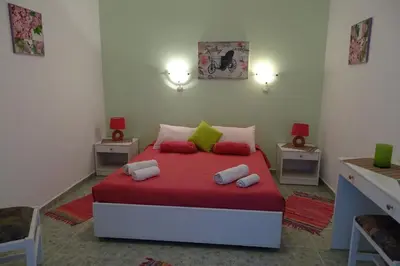 a bedroom with a bed with red sheets and green pillows at Green Garden Studios in Koskinou