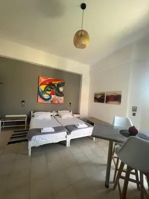 a bedroom with two beds and a table with chairs at Green Garden Studios in Koskinou