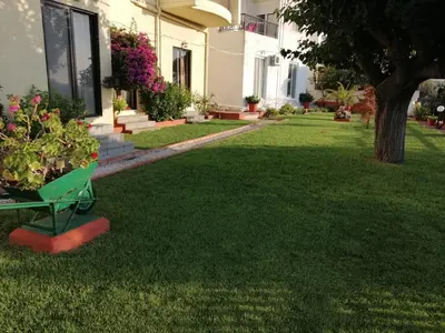 a yard with green grass and a building at Green Garden Studios in Koskinou