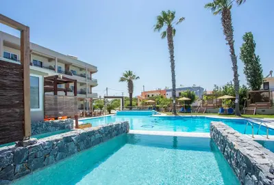 a swimming pool in a resort with palm trees at Dias Studios & Suites in Faliraki