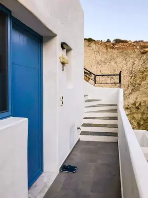 a staircase with a blue door next to a building at Pontoria Stegna Studios in Archangelos
