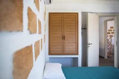 a room with a bed and a wooden cabinet at Pontoria Stegna Studios in Archangelos