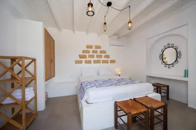 a white bedroom with a bed and a mirror at Pontoria Stegna Studios in Archangelos