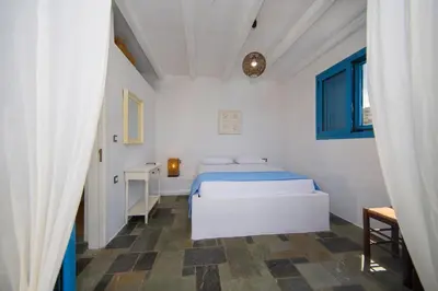 a white bedroom with a bed and a window at Pontoria Stegna Studios in Archangelos