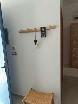 a room with a white wall with a shelf and a stool at Pontoria Stegna Studios in Archangelos